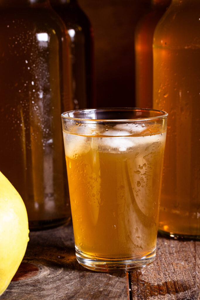 Quitten-Kombucha im Glas, dahinter Flaschen
