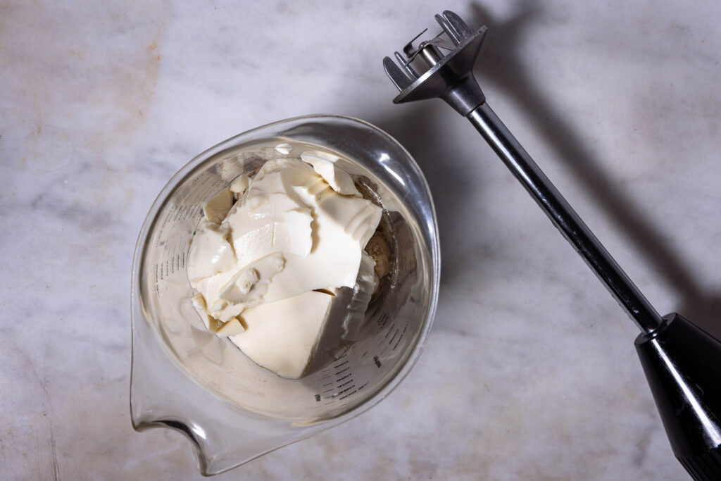 Verschiedene Zutaten in einem Messbecher. Daneben liegt ein Pürierstab.