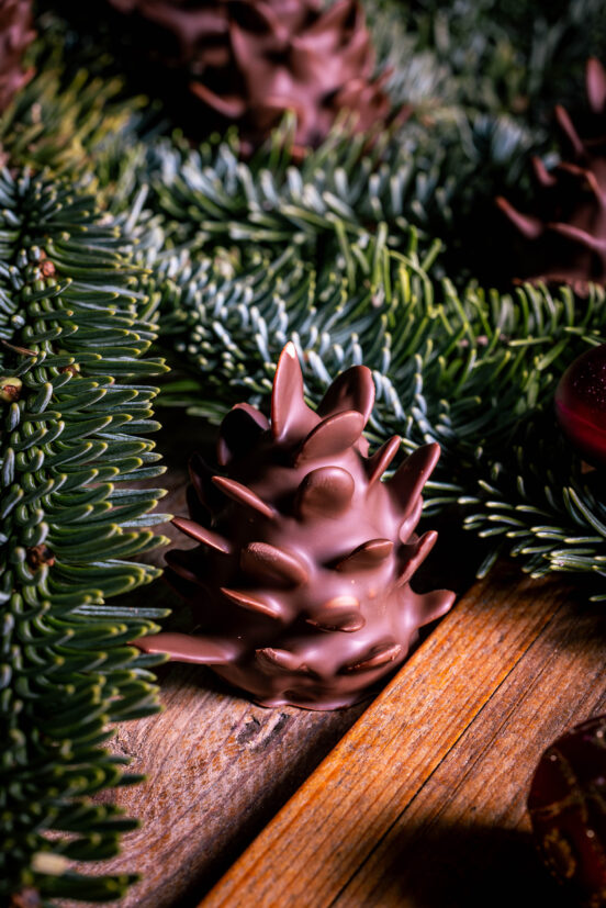 Schokozapfen - Marzipan-Tannenzapfen - dekorativ in Tannenzweigen platziert.