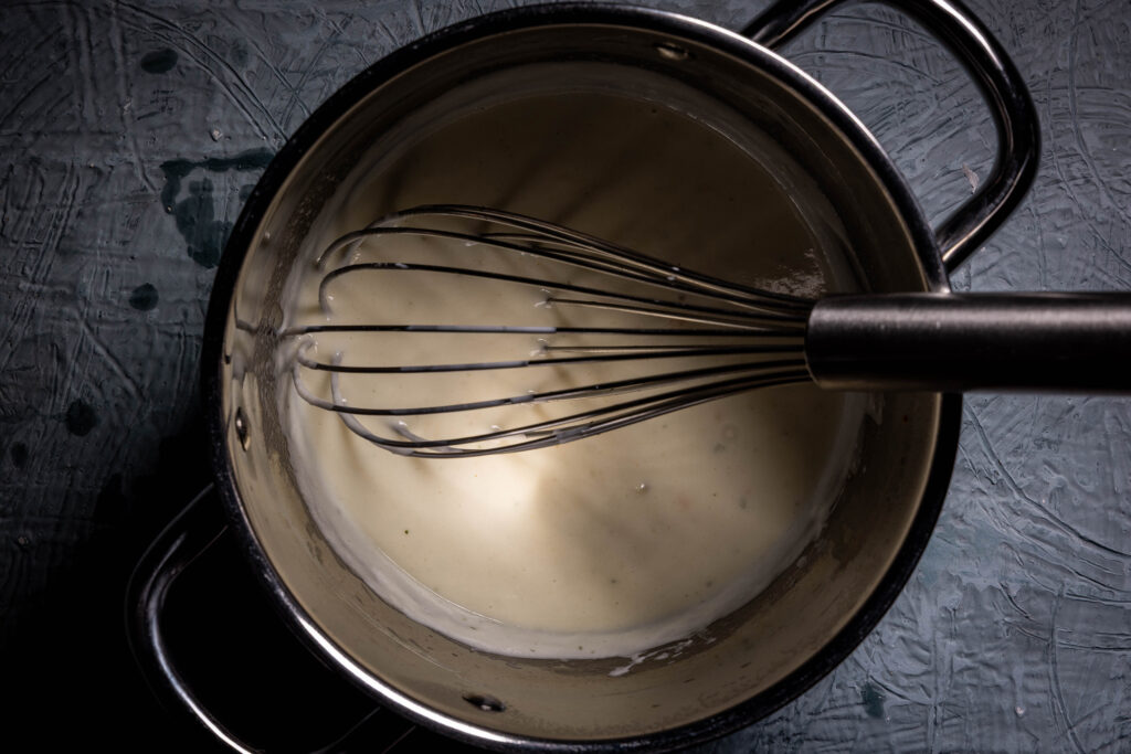Eine vegane Sahnesauce wird in einem Topf zubereitet.