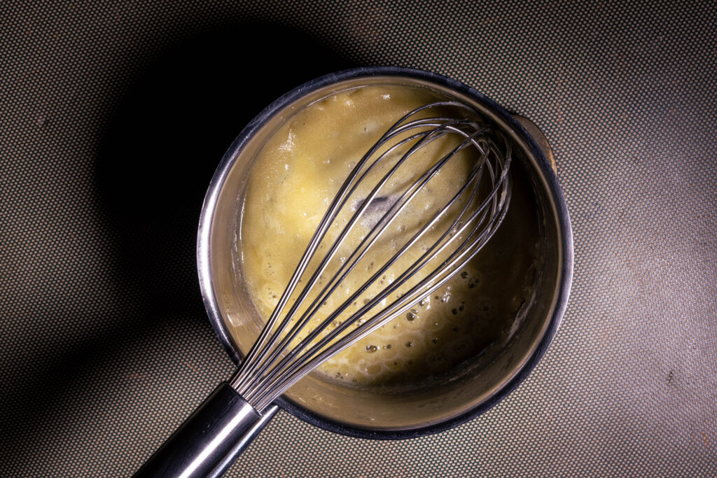 Eine vegane Mehrschwitze blubbert in einem Topf mit Schneebesen.