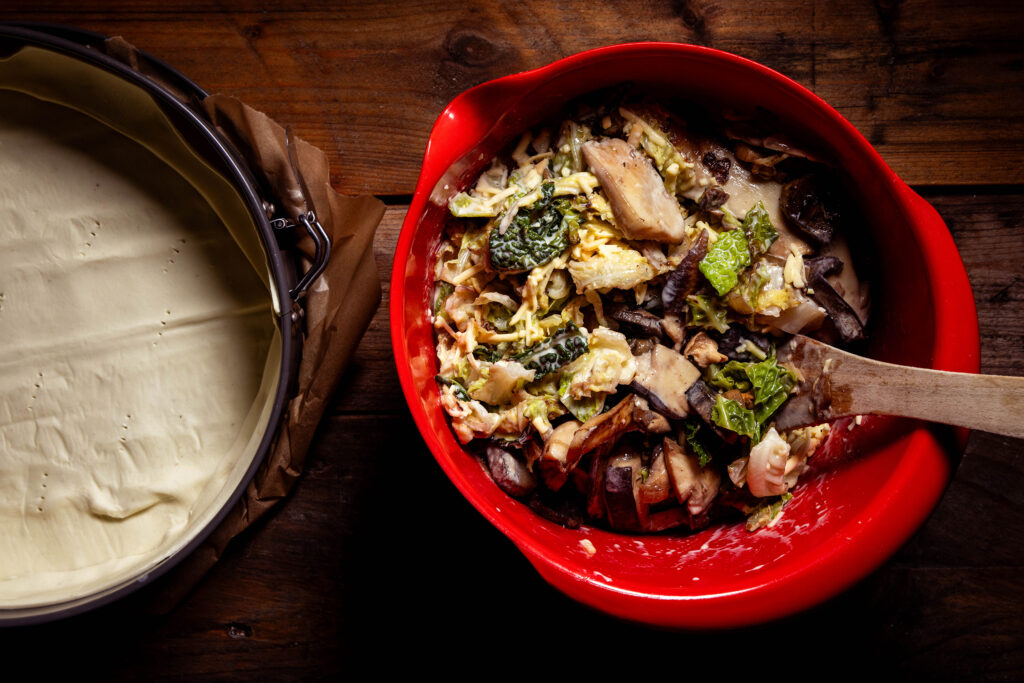 Eine Quichefüllung mit Wirsing und Waldpilzen in einer Schüssel.