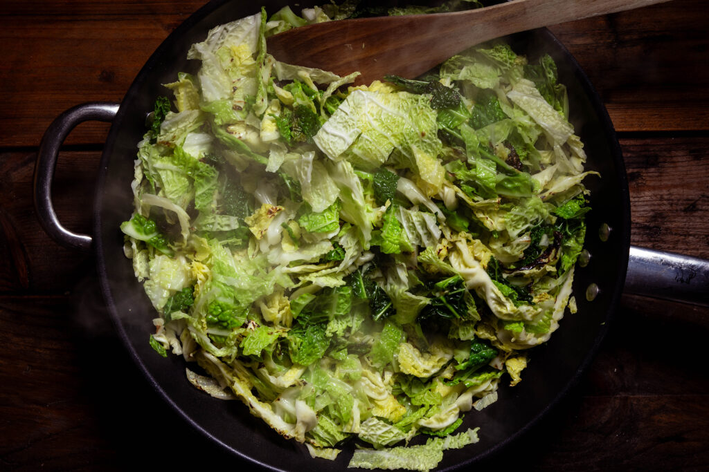 Wirsing brät in einer großen Pfanne.