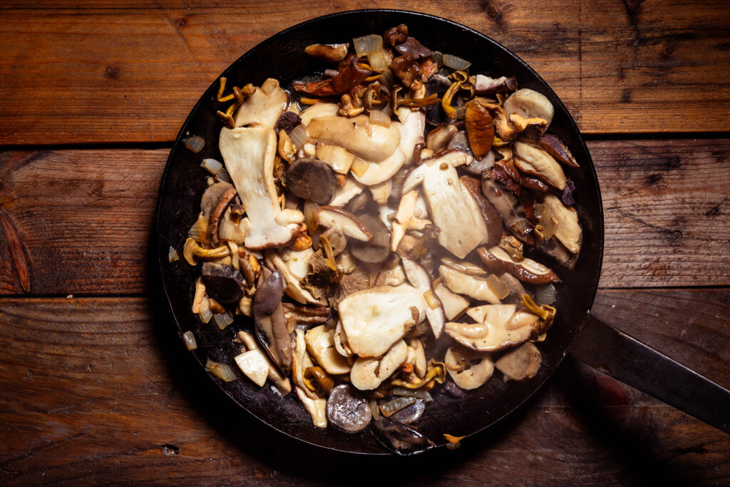 Gemischte Waldpilze braten in einer Pfanne.