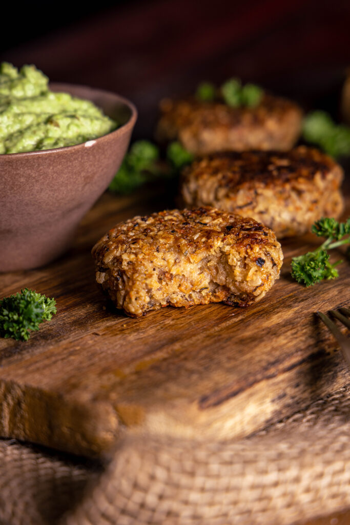 Zero Waste Bouletten - aus Bratensaucentrester - auf einem Holzbrett mit einer Schale grünem Dip, eine ist angebissen.