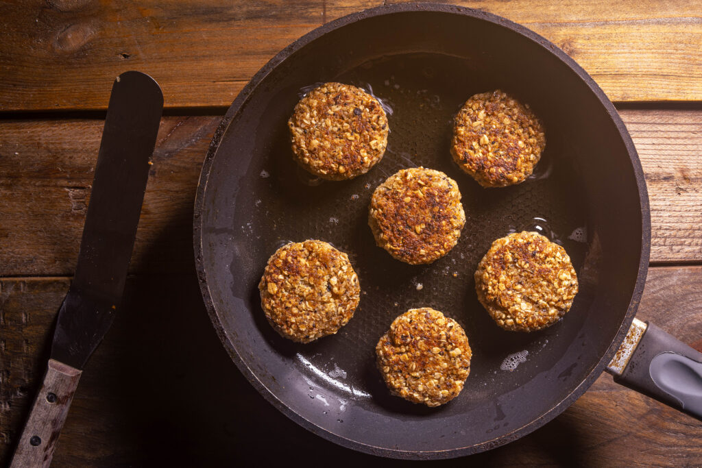 Vegane Bouletten aus Bratensaucentrester braten in einer Pfanne.