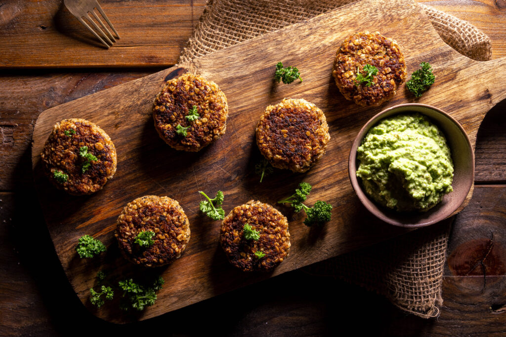 Zero Waste Bouletten - aus Bratensaucentrester - auf einem Holzbrett mit einer Schale grünem Dip.
