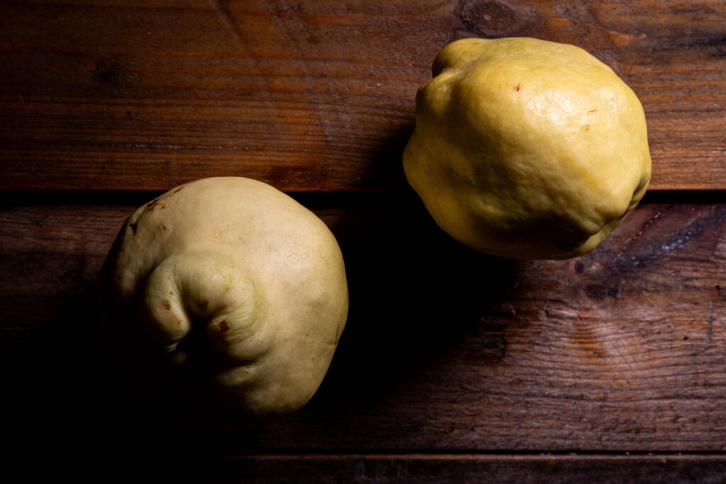 2 Quitten auf einem alten Holztisch.