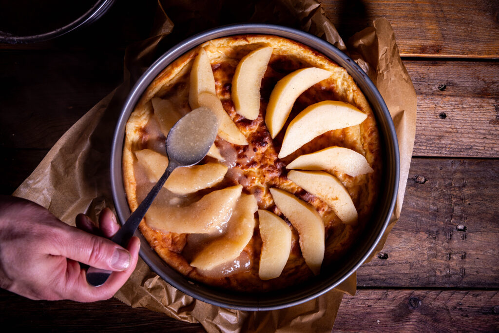 Kochend heißer Quittenspiegel wird auf dem Käsekuchen verteilt.