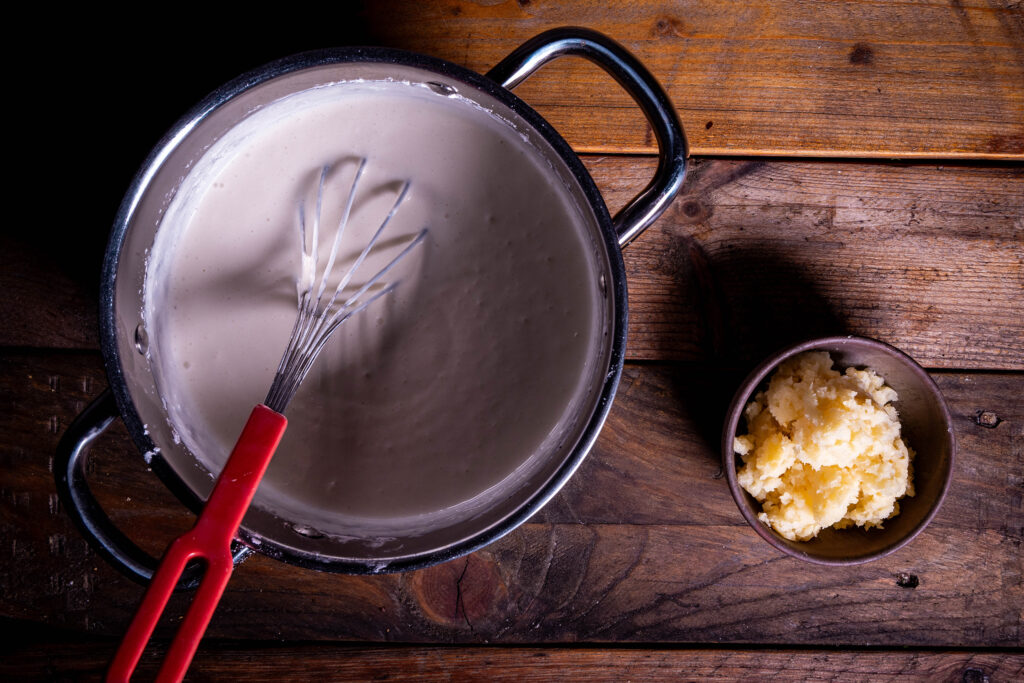 Eine vegane Puddingmasse wird gekocht. Daneben eine Schale fermentierte, pürierte Quitten.