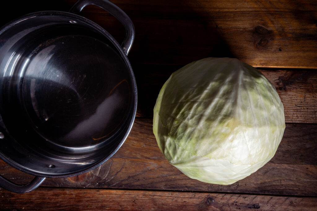 Ein Kopf Weißkohl und ein Kochtopf mit Waasser darin.