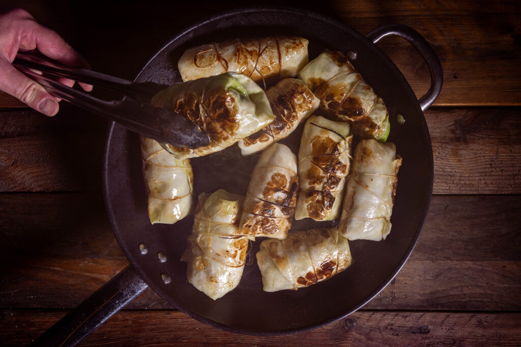 Kohlrouladen werden in einer Pfanne angebraten.