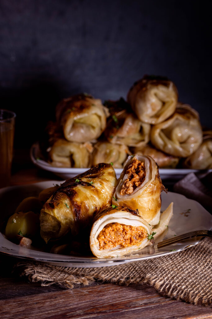 Vegane Kohlrouladen - klassisch in Sauce, eine ist angeschnitten, so dass man die Füllung sieht.