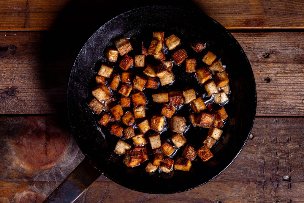 Räuchertofuwürfel braten in einer Pfanne.