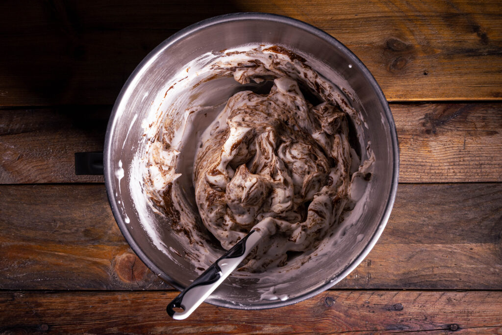 Schoko-Spekulatius-Creme wird unter veganen Eischnee gehoben.