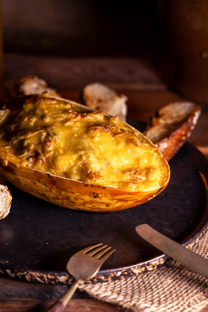 Überbackener Spaghettikürbis gefüllt mit deftigem Pulled-Jackfruit-Pilz-Ragout, darauf noch eine cremig-krosse, vegane Käsekruste.