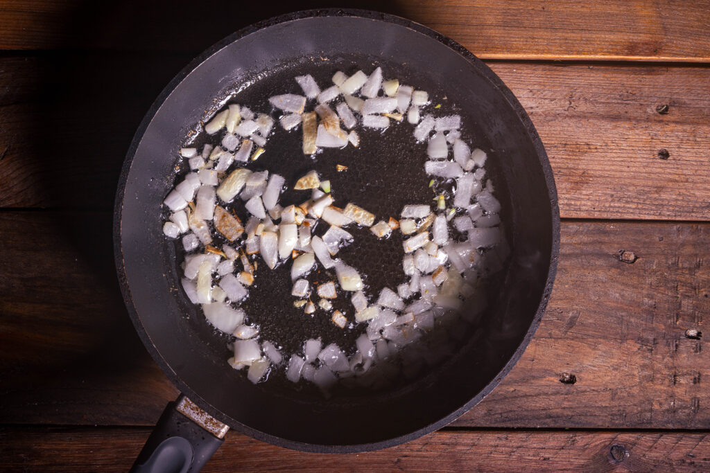 Zwiebelwürfel braten in einer Pfanne.
