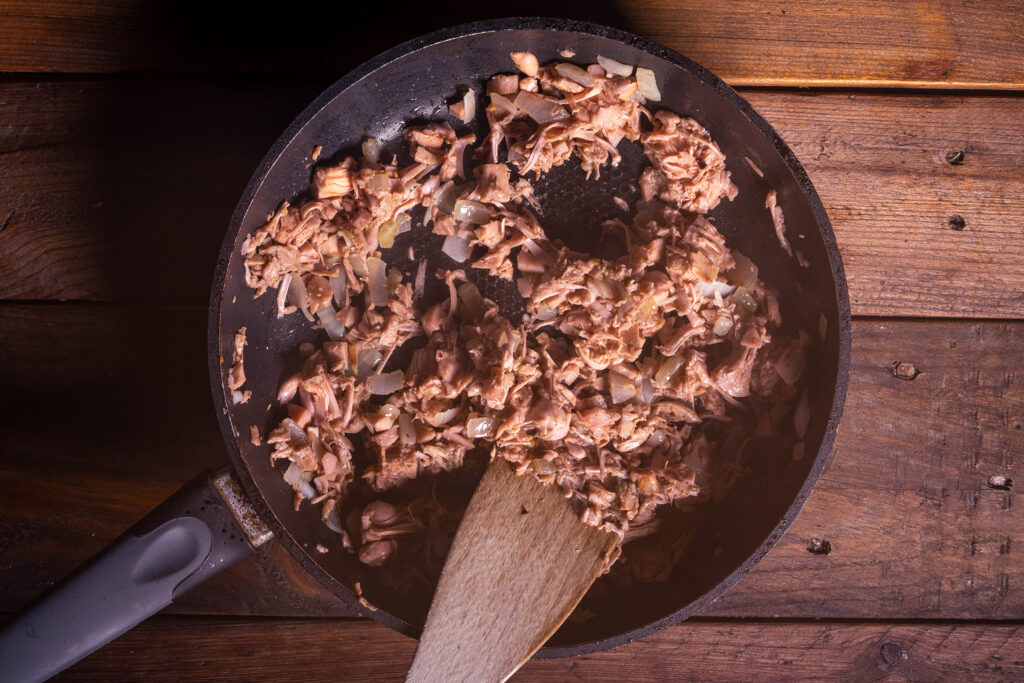 Gewürzte Jackfruit brät in einer Pfanne.