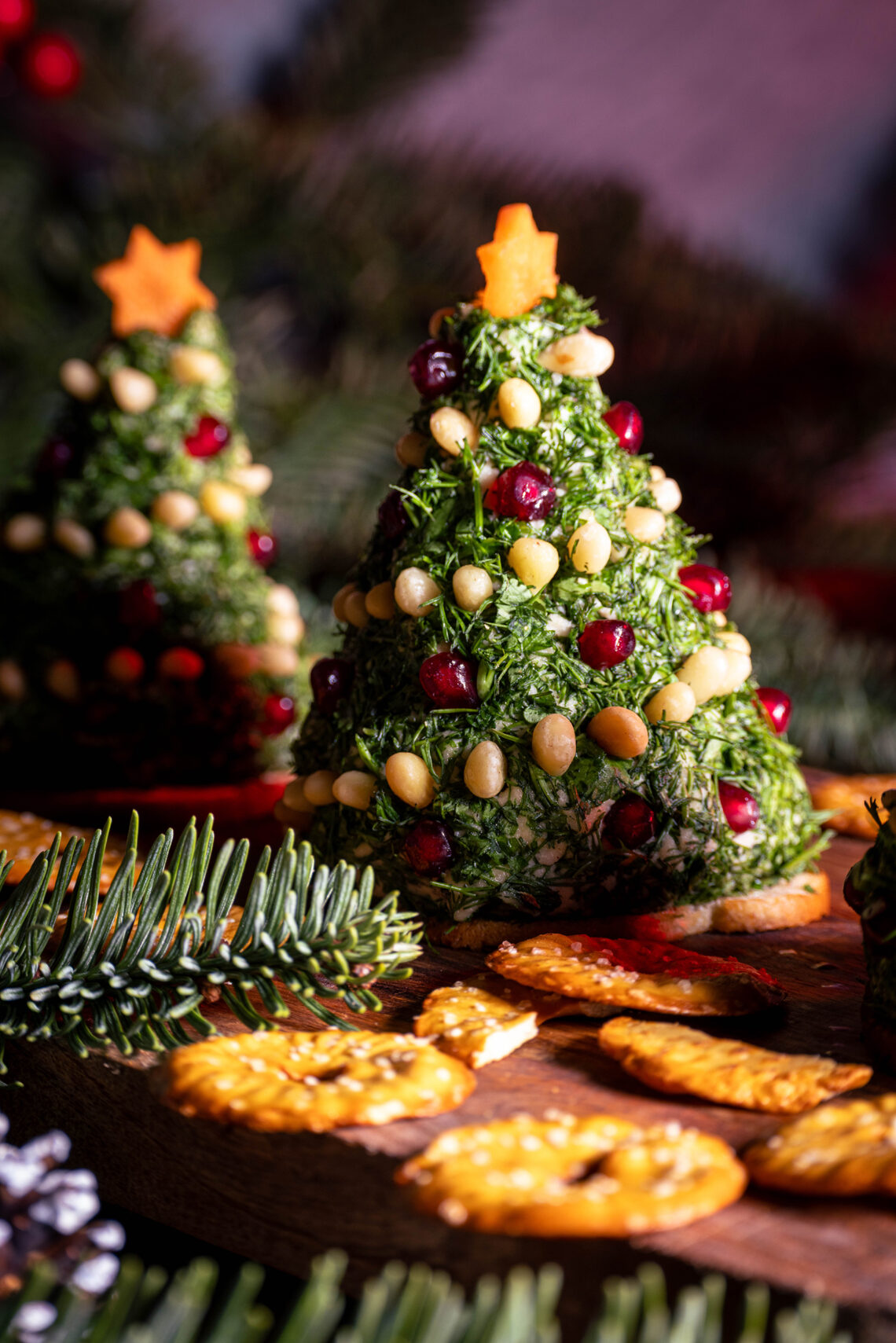 Vrischkäse-Weihnachtsbäumchen - zwei Stück mit Crackern auf einem Holzbrett.