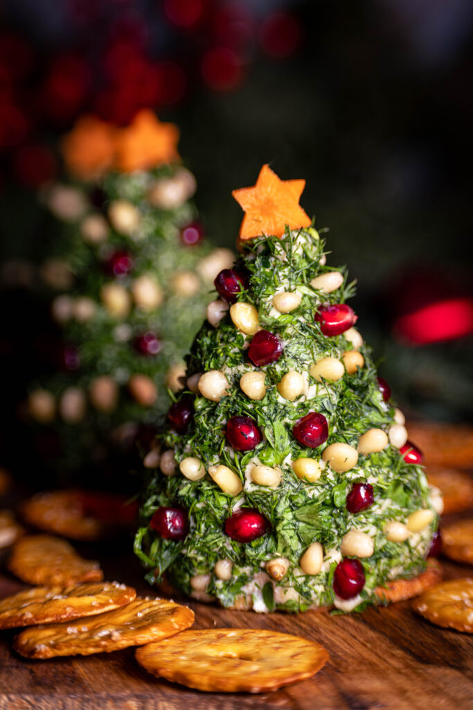 Vrischkäse-Weihnachtsbäumchen - festlich dekotiert - mit Crackern auf einem Holzbrett.
