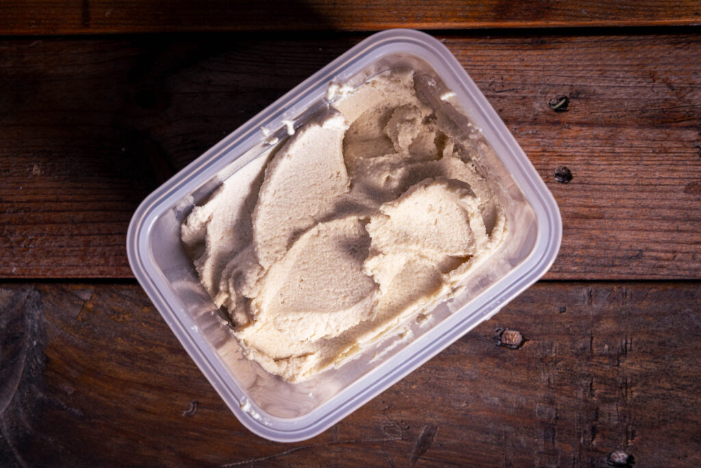 Vegane Frischkäsemasse in einer Plastikdose.