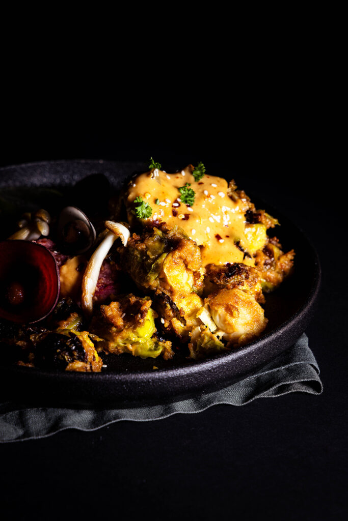 Brussels sprouts roasted in Satay sauce on a plate with other sides.