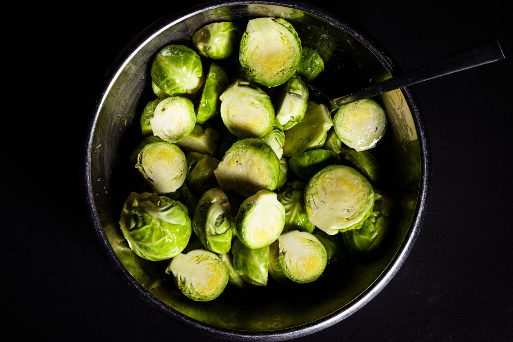 Brussels sprouts mixed with the olive oil and salt in a bowl.