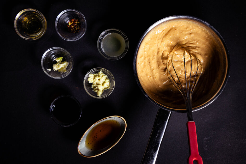 Peanut suace is being prepared. Ingredients on a black table.