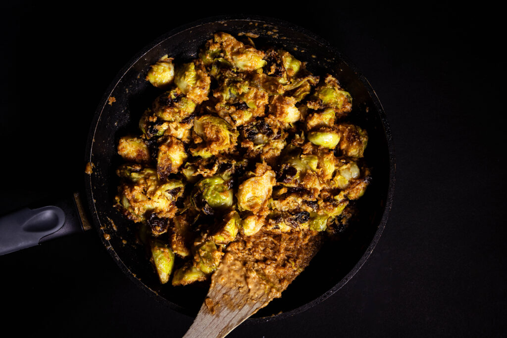 Brussels sprouts with satay sauce are frying in a pan.