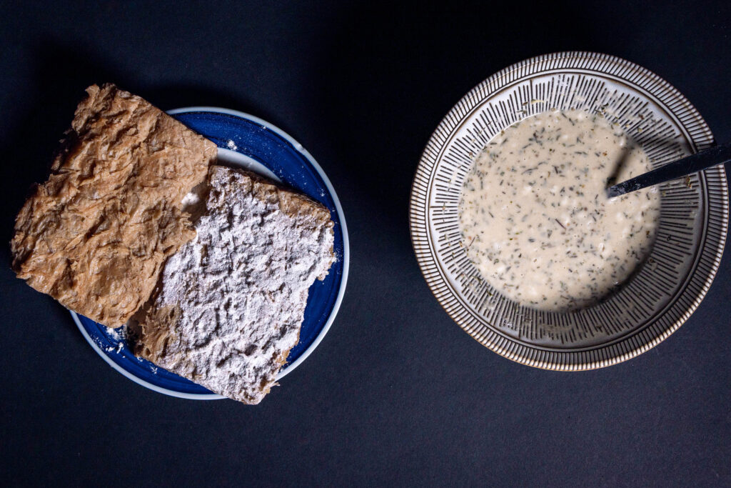 Vegane Big Steaks werden in Mehl gewendet. Daneben eine Schale mit flüssiger Panade.