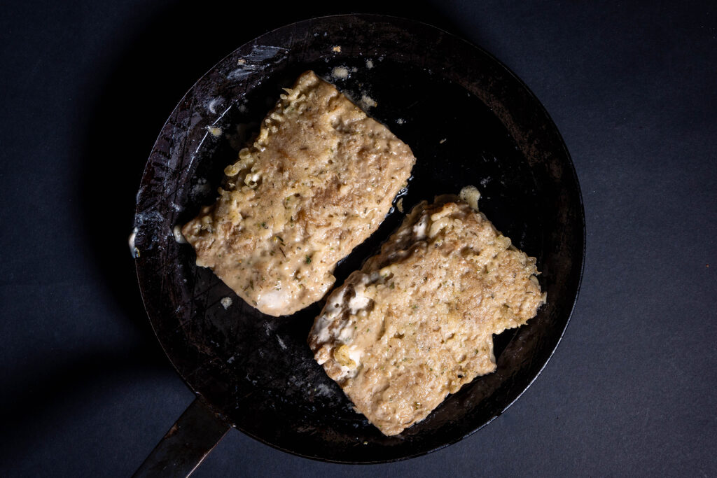 Chicken Filets werden in einer Pfanne mit Öl gebraten.