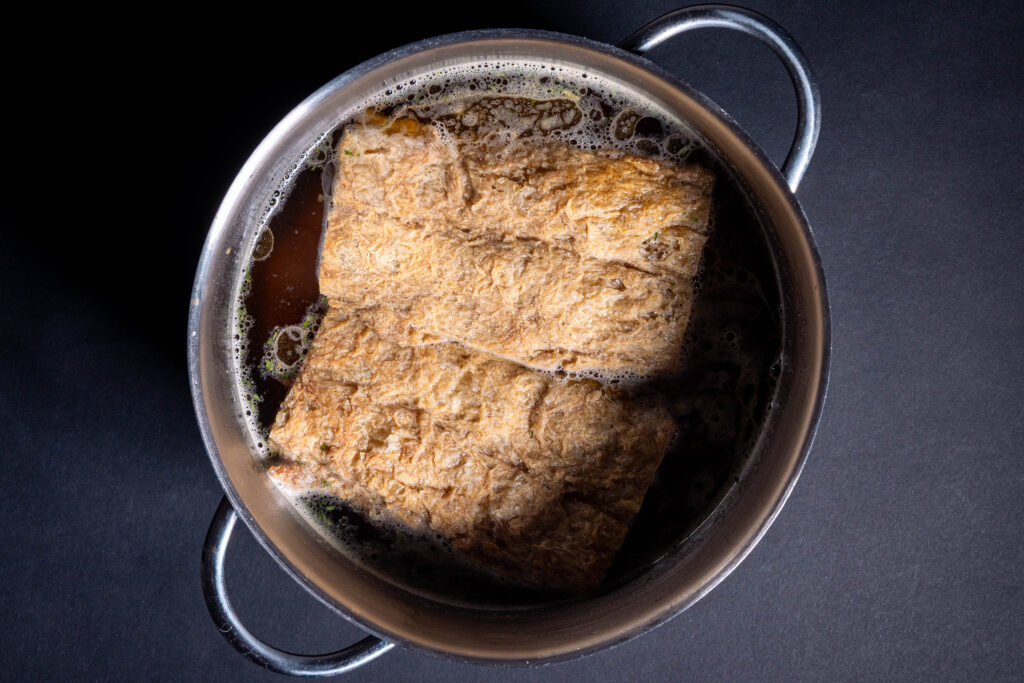 2 Soja Big Steaks garen in einem Topf mit gewürzter Brühe.