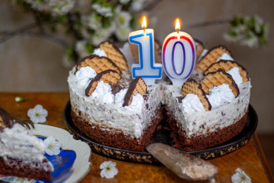 Eine 10 in Form von brennenden Geburtstagkerzen auf einer Schokokusstorte.