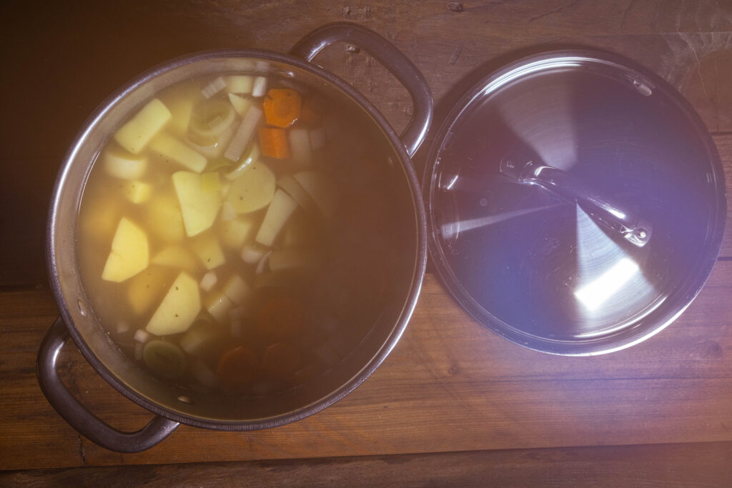 Eine heiße, dampfende Kartoffelsuppe wird in einem Kochtopf zubereitet.