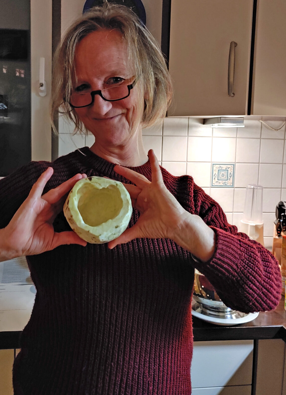 Veronika mit einem ausgehöhlten Sellerie in der Hand in der Küche