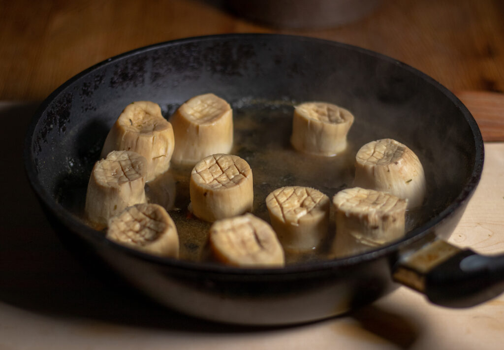 Vegan king oyster mushrooms cooking in their broth.