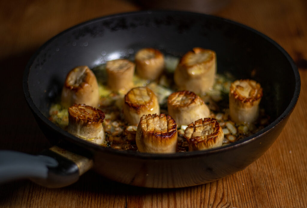 Searing king oyster mushrooms on both sides with garlic and shallot.