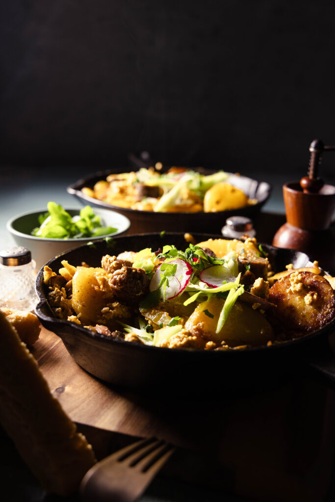 Veganes Bauernfrühstück mit Würstchen und Pilzen in einer gusseisernen Pfanne.