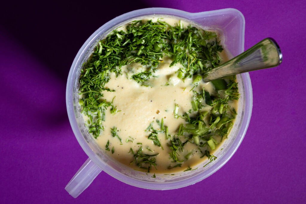 Blattsenf und Lauchzwiebeln werden in eine vegane Omelettemasse eingerührt.