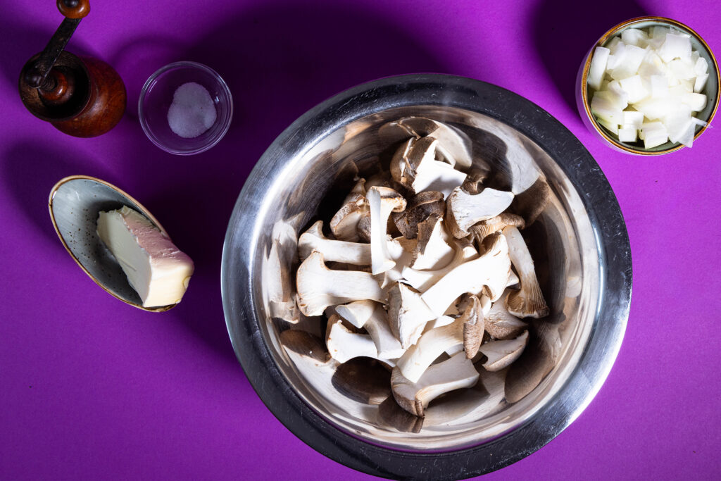 Die Kräuterseitlinge in Scheiben schneiden und die Zwiebel würfeln.