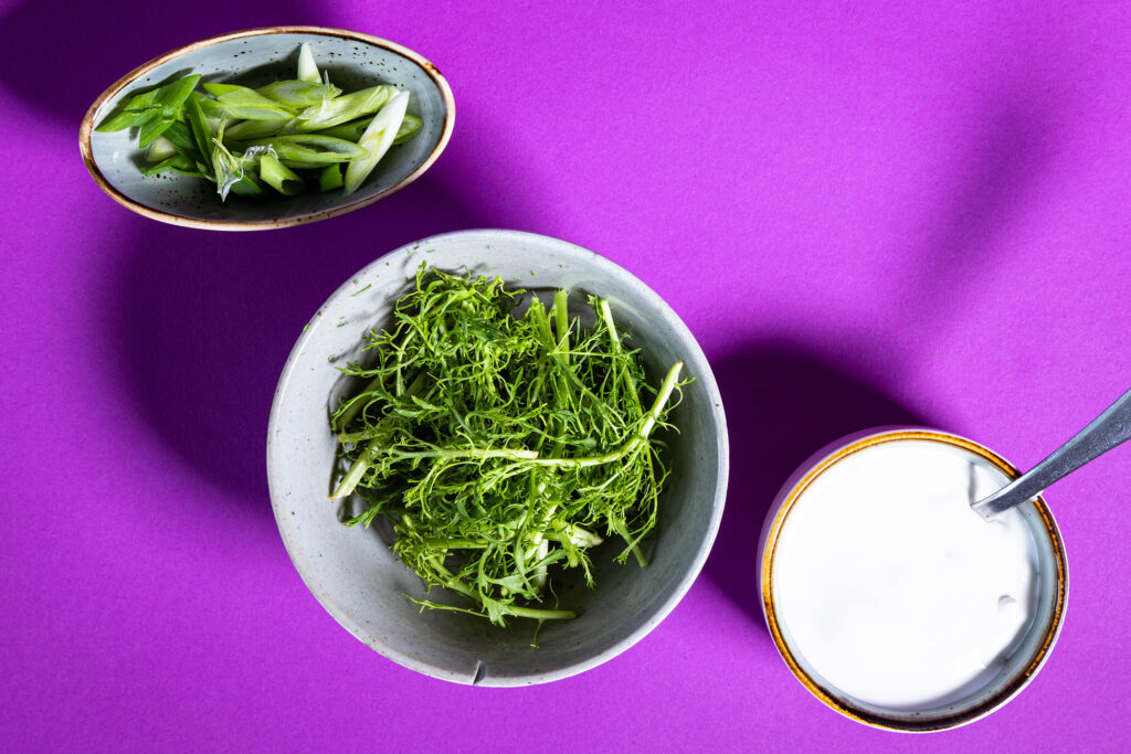 Vegane Creme Fraiche, frischer Blattsenf und Frühlingszwiebelringe.