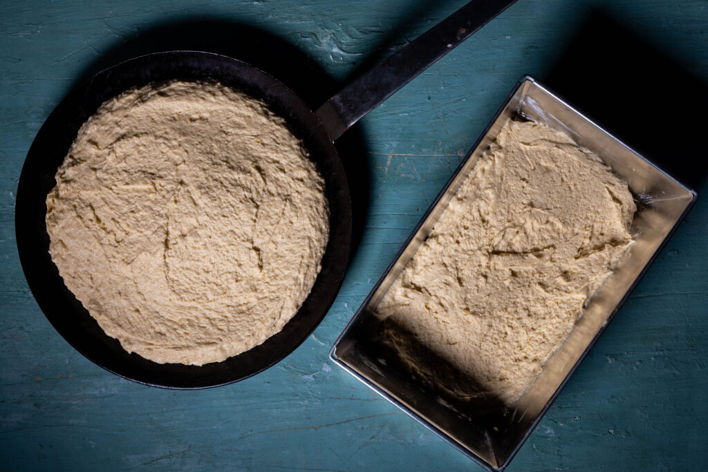 Roher Cornbreadteig in einer Pfanne und in einer Kastenform.