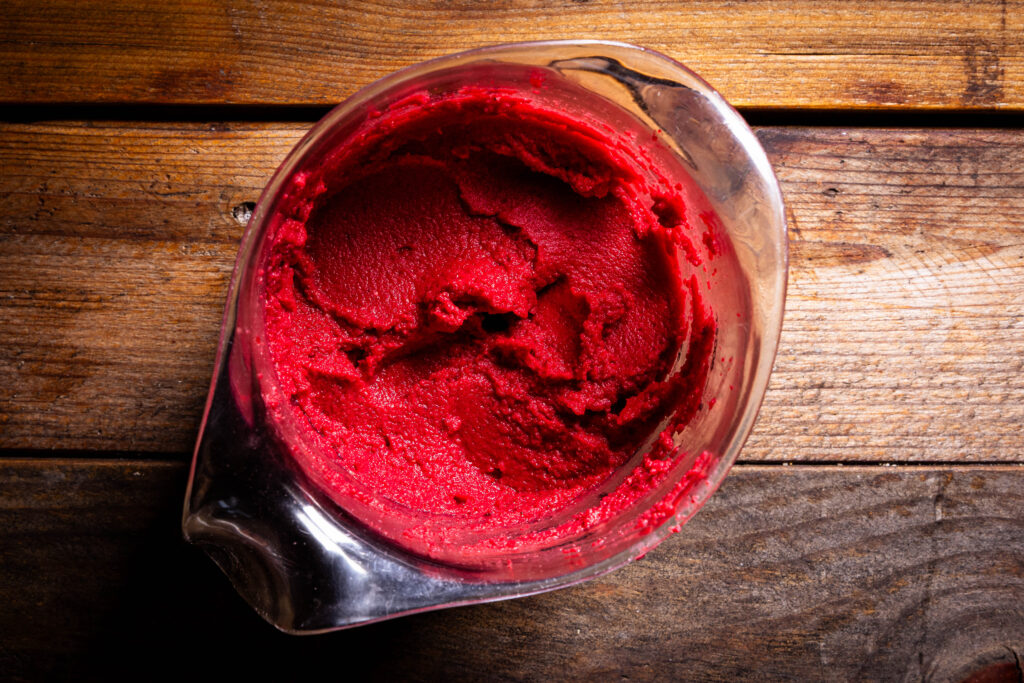 Frisch pürierter Hummus mit Rote Beete in einem Messbecher.