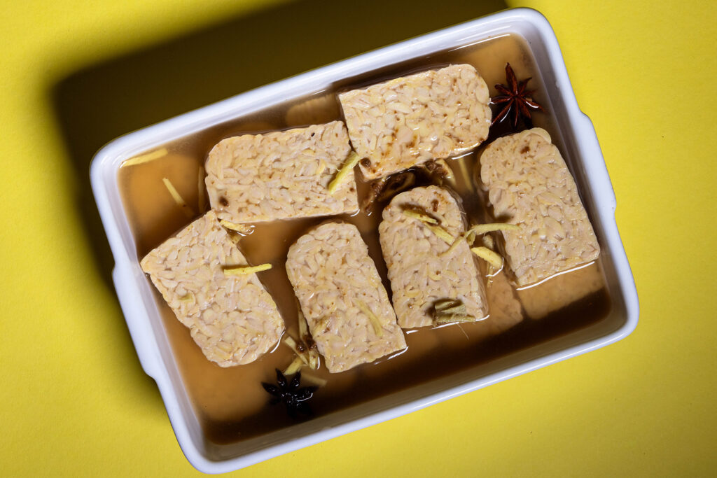 Tempeh liegt in einer Marinade.