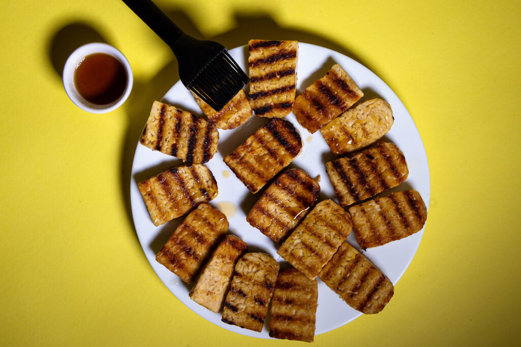 Gegrillter Tempeh wir mit einem Küchenpinsel mit Ahornsirup lasiert.