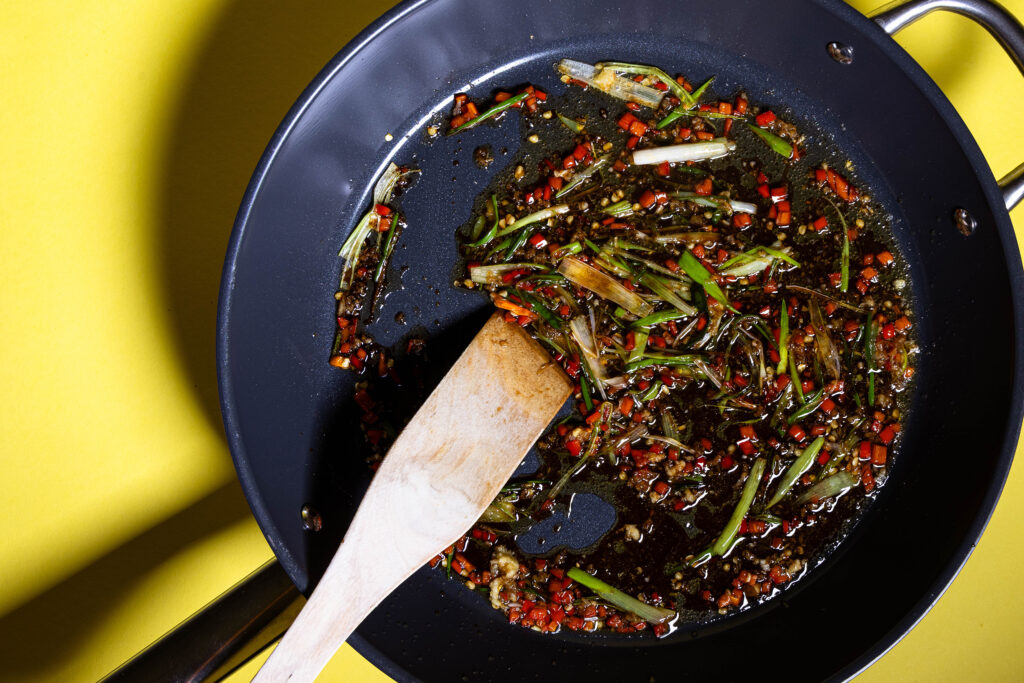 Eine Chilisauce wird in einer Pfanne zubereitet.