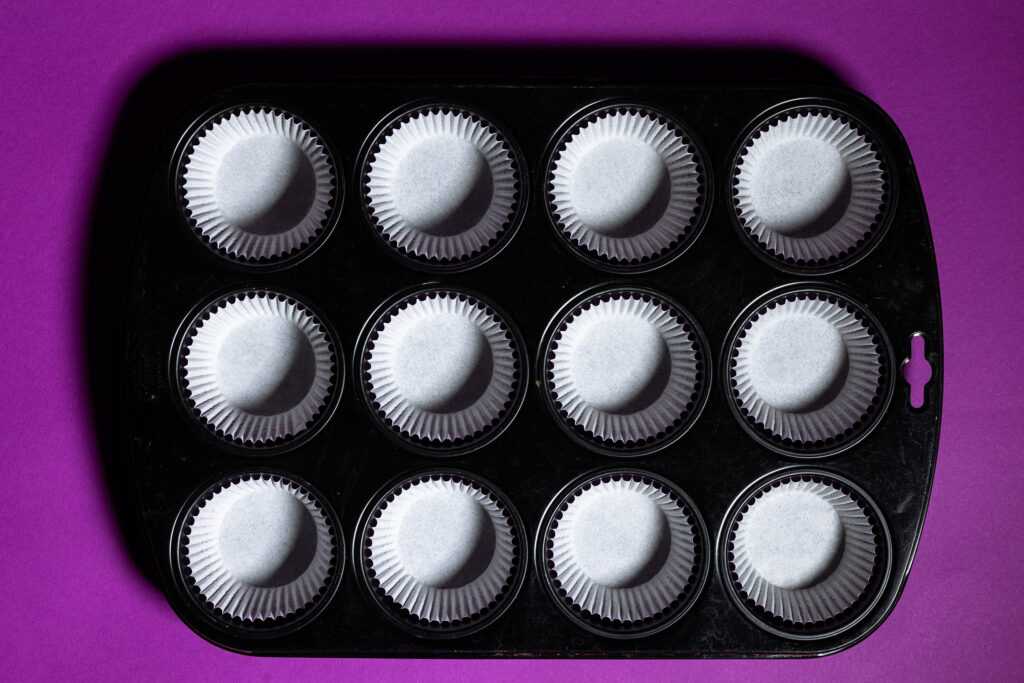 Ein Muffinblech mit Papierförmchen ausgekleidet.