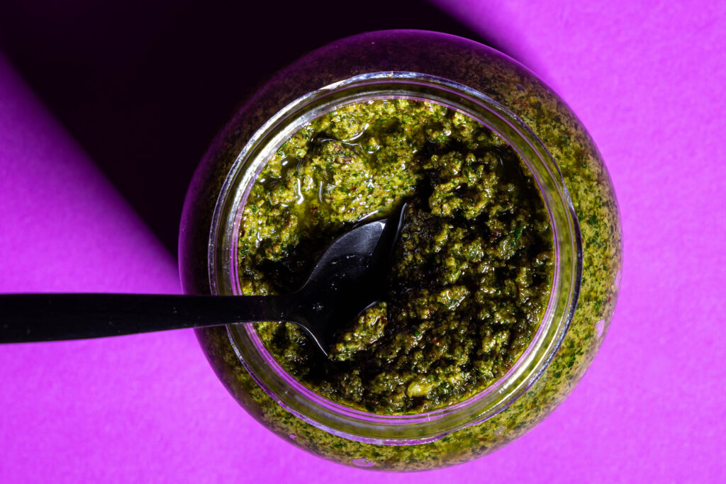 Pesto mit einem Löffel in einem Schraubglas.