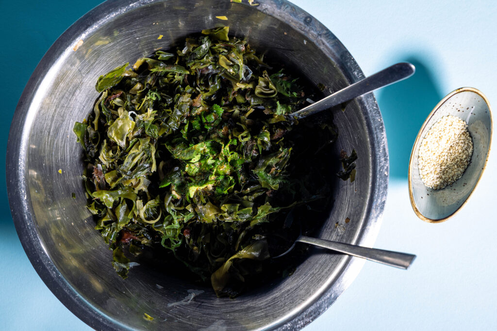 Japanischer Wakame-Salat wird in einer Metallschüssel vermengt.