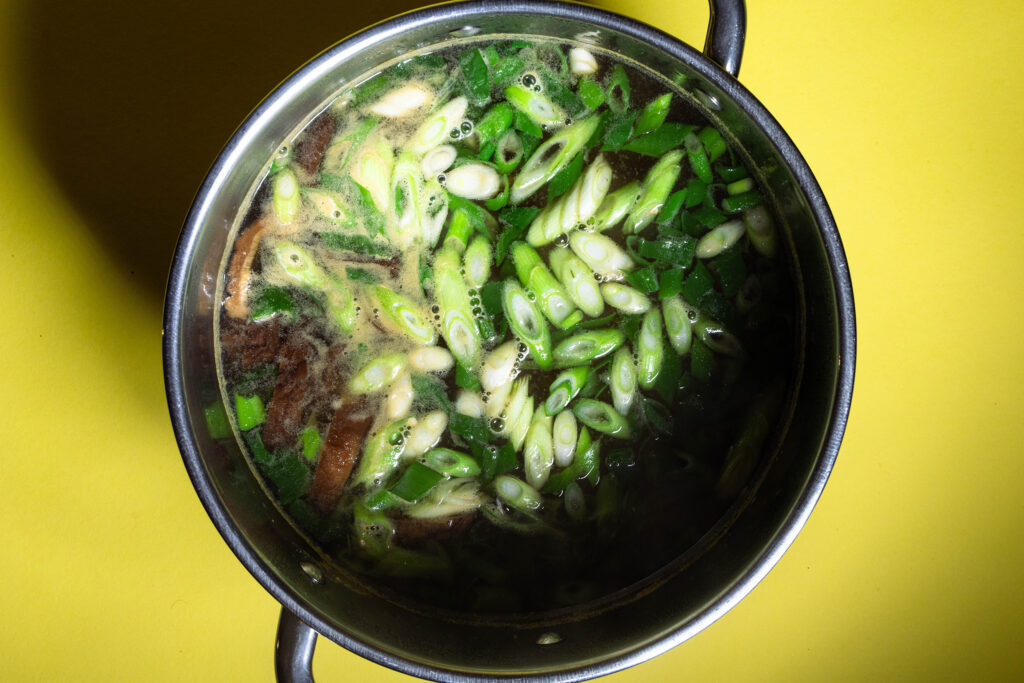 Miso-Suppe mit Frühlingszwiebeln, Shitake und Karotte in einem Topf.